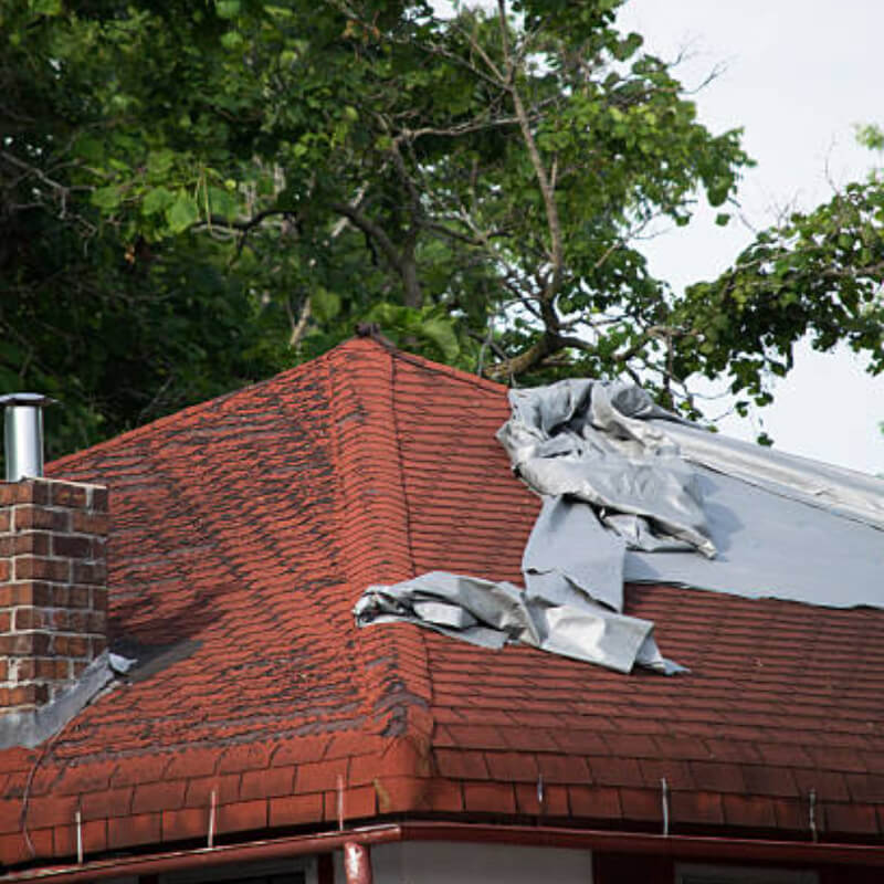 Image depicting damage caused by high winds leading to a leaking roof and the need for roof repair emergency.